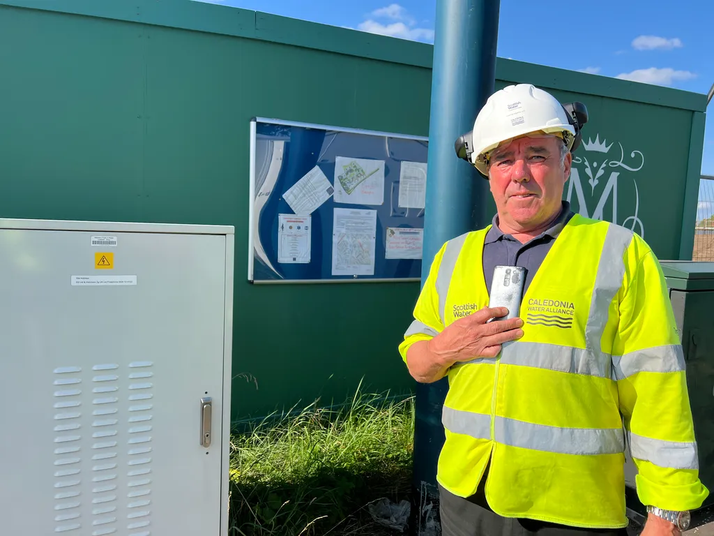 Scottish Water fieldworker in PPE recording a safety assessment on a phone